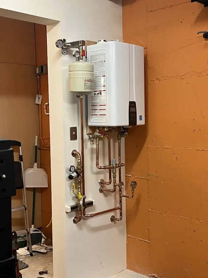 Plumbing technician inspecting water heater connections in Selmer